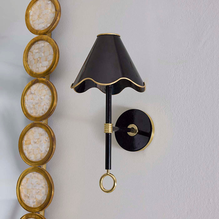Decorative wall sconce with black and gold design on a light gray wall.