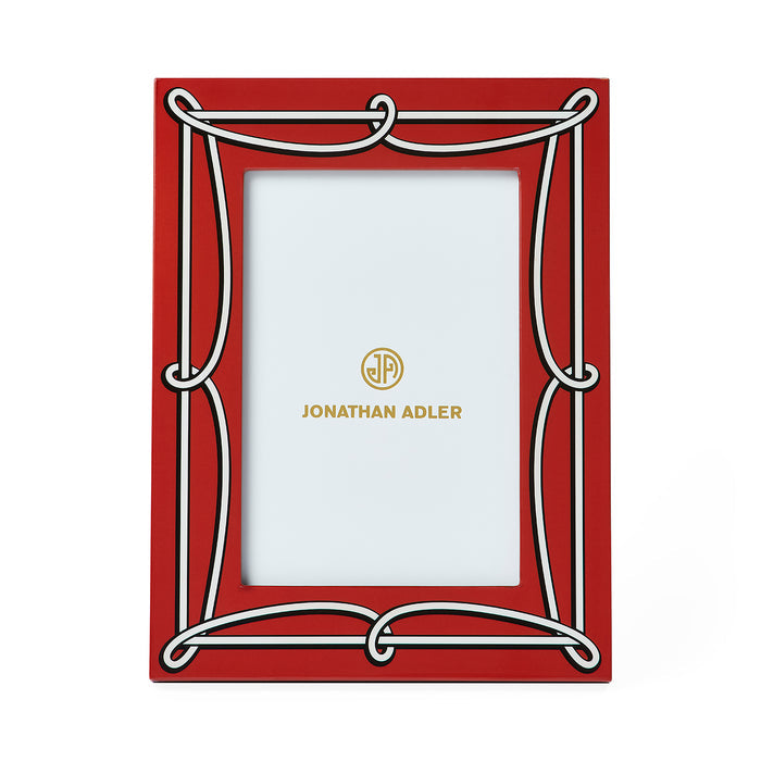 A red picture frame with a white decorative border and gold Jonathan Adler branding printed on the insert, shown against a plain white background.