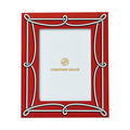 A red rectangular picture frame with an ornate white decorative border and gold Jonathan Adler branding printed in the center of the insert.