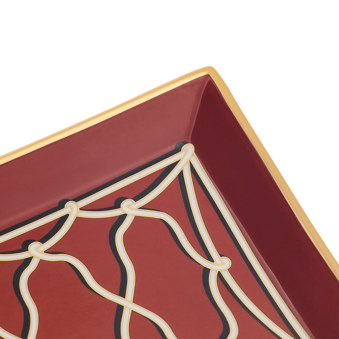 Close-up of a square decorative tray corner with a deep burgundy interior, cream web-like line pattern, and a gold rim on a white background.