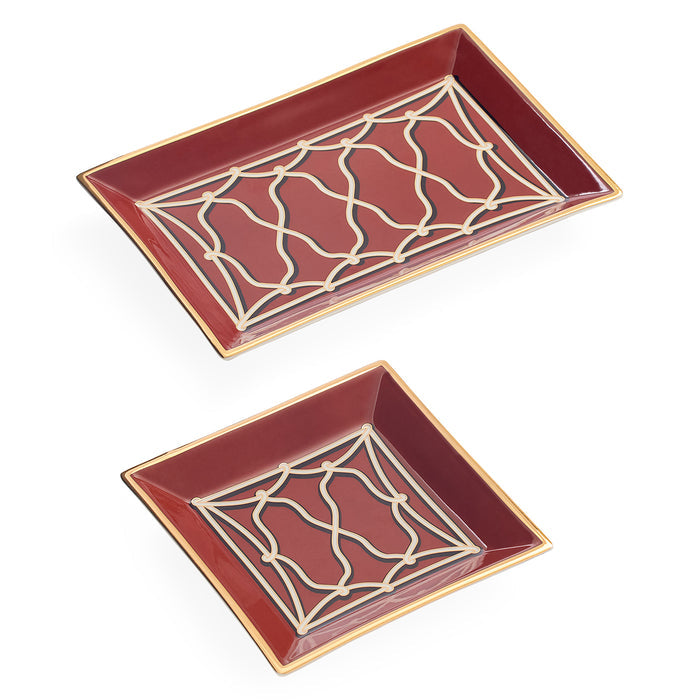 Two decorative ceramic trays in a matching set, one rectangular and one square, both in deep red with a cream geometric trellis pattern and gold trim, shown on a white background.