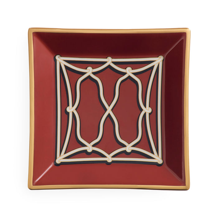 A square ceramic dish with a deep burgundy red interior, featuring a cream-colored geometric trellis pattern in the center and a thin gold rim, shown against a plain white background.