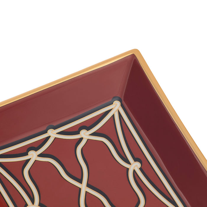 Close-up of a square decorative tray corner with a deep burgundy interior, cream geometric lattice pattern, and a gold-toned rim on a white background.