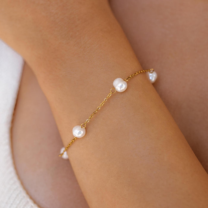 An 18K gold-plated bracelet with freshwater pearls, featuring a lobster clasp, worn on a person's wrist.