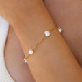 An 18K gold-plated bracelet with freshwater pearls, featuring a lobster clasp, worn on a person's wrist.