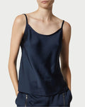 A person wears the Saint Art Elliot Navy Charmeuse Camisole by Saint Art NY with matching pants, standing hands in pockets against a plain background.