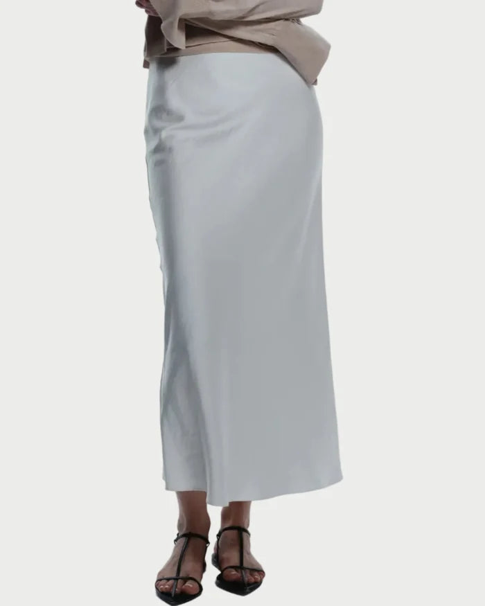Woman wearing a beige sweater and white skirt on a white background