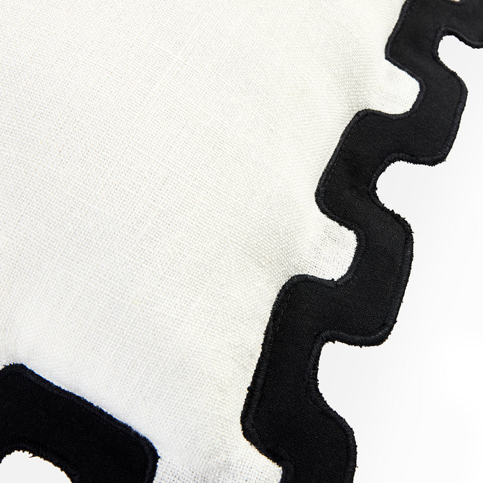 Close-up of a white textured fabric with a bold black wavy scalloped border trim.