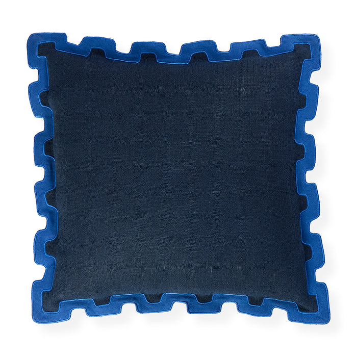 A square throw pillow in dark navy blue fabric with a contrasting bright blue jigsaw puzzle-edge border, shown on a plain white background.