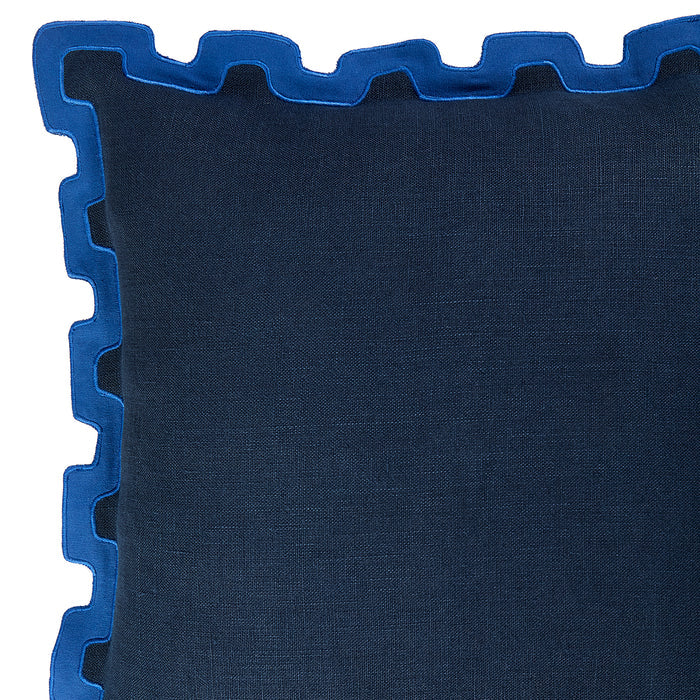 Close-up of a dark blue textured throw pillow with a contrasting bright blue scalloped edge trim, shown against a white background.