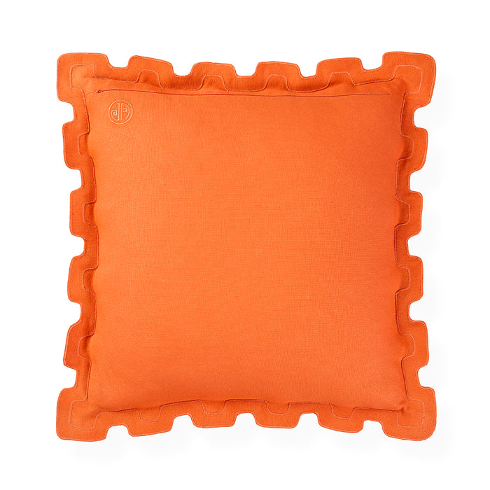 A square orange throw pillow with a decorative wavy ruffled border, shown flat against a solid white background. A small circular embroidered logo is visible in the top-left corner.