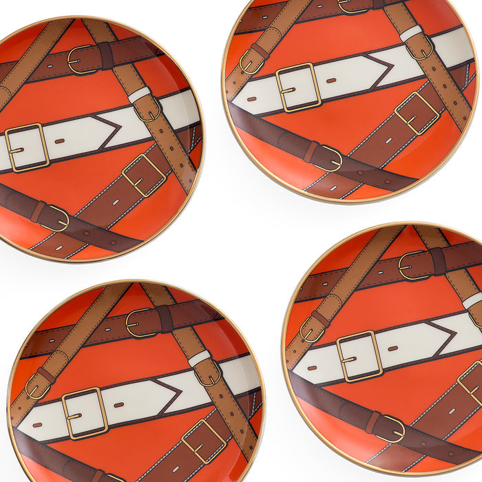 Four round decorative plates arranged in a 2x2 grid, featuring a repeating pattern of brown leather straps and buckles over a bright orange background with white arrow-like shapes.