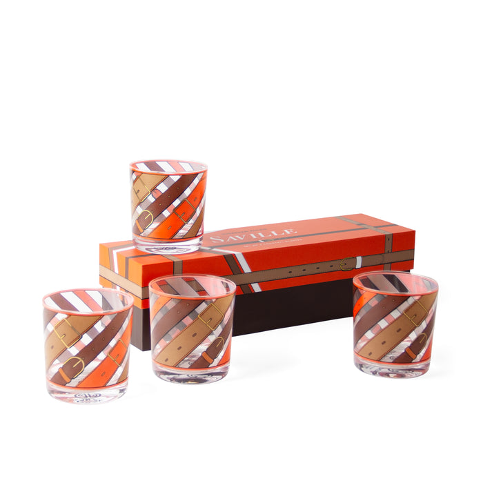 Four clear glass tumblers with an orange, brown, and white leather-strap pattern, arranged around a matching orange and brown presentation box on a white background.