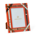 Jonathan Adler picture frame with a bright orange background and an all-over brown and cream leather-buckle print, shown standing on a small matching base against a white background.