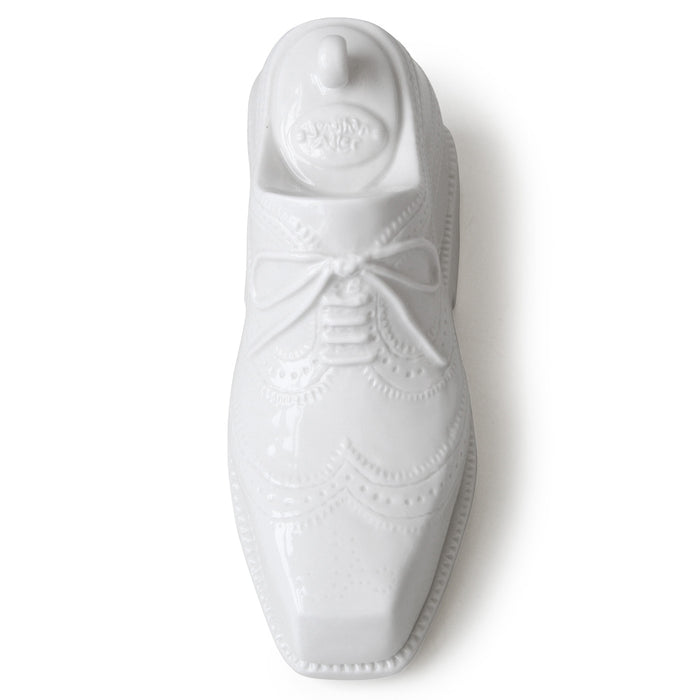 White ceramic shoe with decorative elements on a white background
