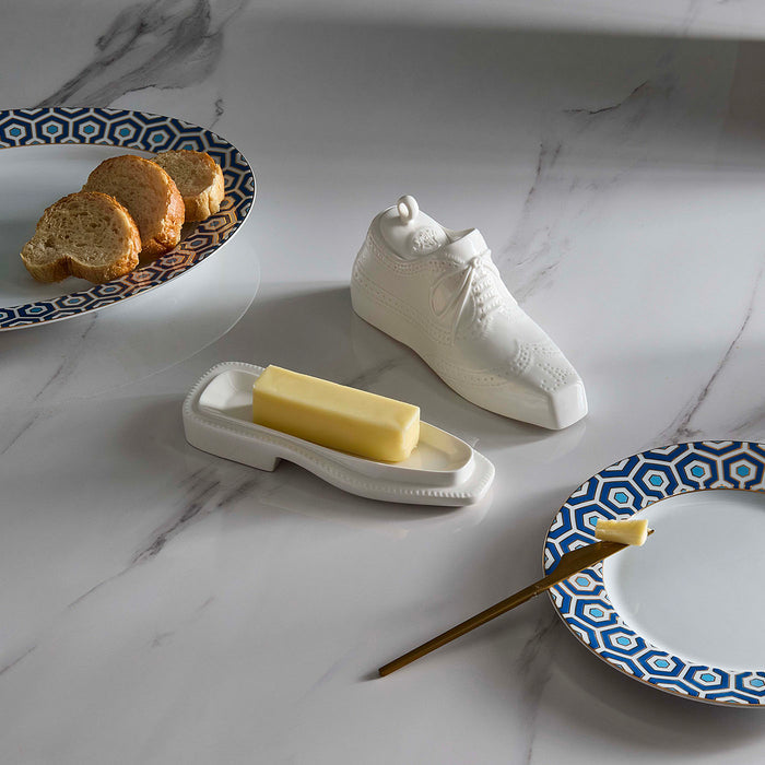 Butter dish shaped like a shoe with a bar of butter on a marble surface.