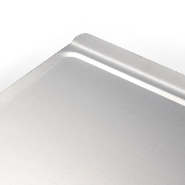 Angled close-up of Small Cookie Sheet showing rimmed corner and brushed stainless surface on white background