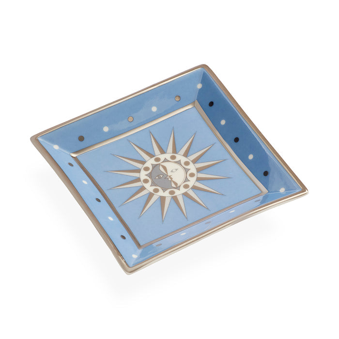 A square ceramic dish with a light blue glaze, featuring a central silver sunburst motif with a small moon and stars, and silver-rimmed edges with white and dark blue polka dots.