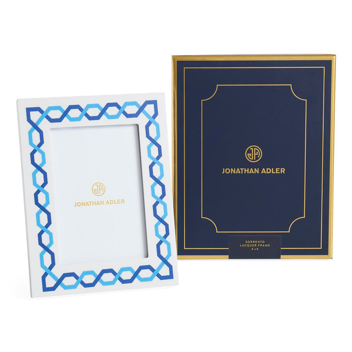 Two Jonathan Adler picture frames, one white with blue geometric design and the other navy with gold lettering.