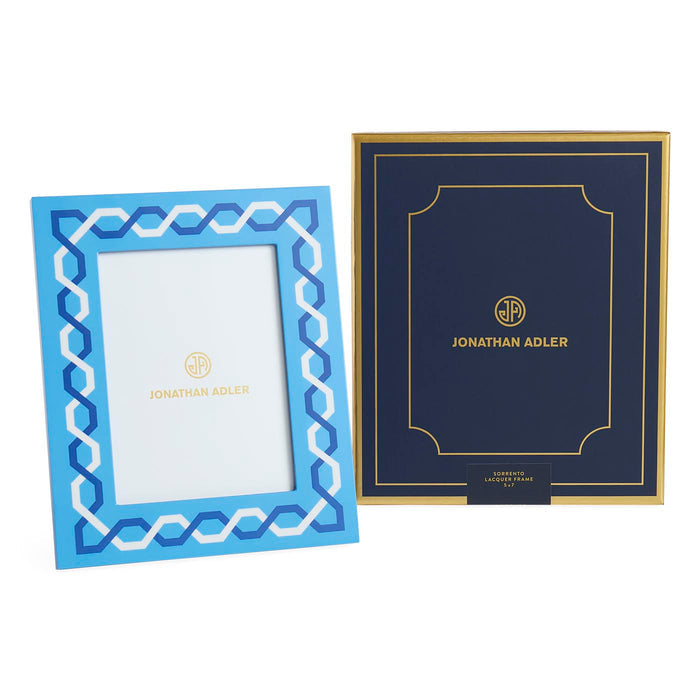 Two Jonathan Adler frames, one blue with geometric pattern and gold text, the other navy with gold border and text.