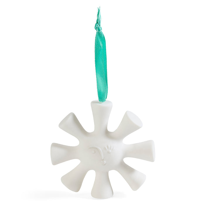 A white ceramic snowflake Christmas ornament with a small embossed face and a teal ribbon hanger, shown on a solid white background.