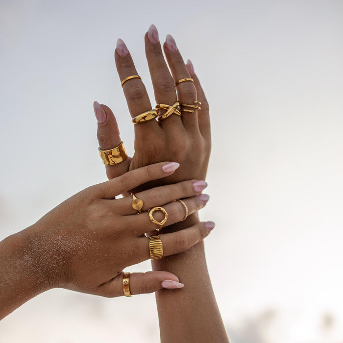 a ring stack featuring many chunky and dainty gold rings to create a cohesive and beautiful ring stack