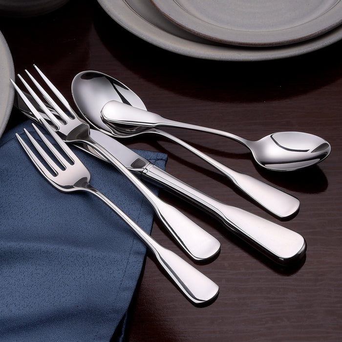 Angled view of Susanna flatware, polished stainless steel forks, knives, and spoons on dark wood with a blue cloth napkin and plates