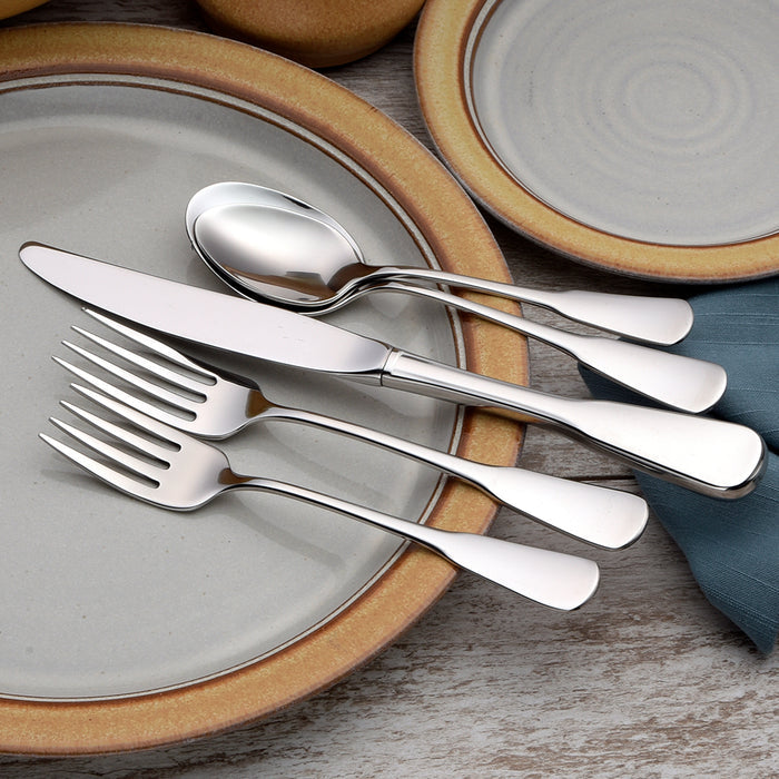 Angled view of Susanna flatware showing mirror polished 18-10 stainless steel on ceramic plates with blue napkin
