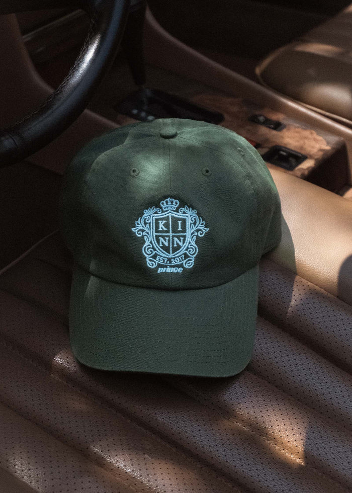 A Kinn x Prince The Club Cap sitting on the driver seat of a vintage car