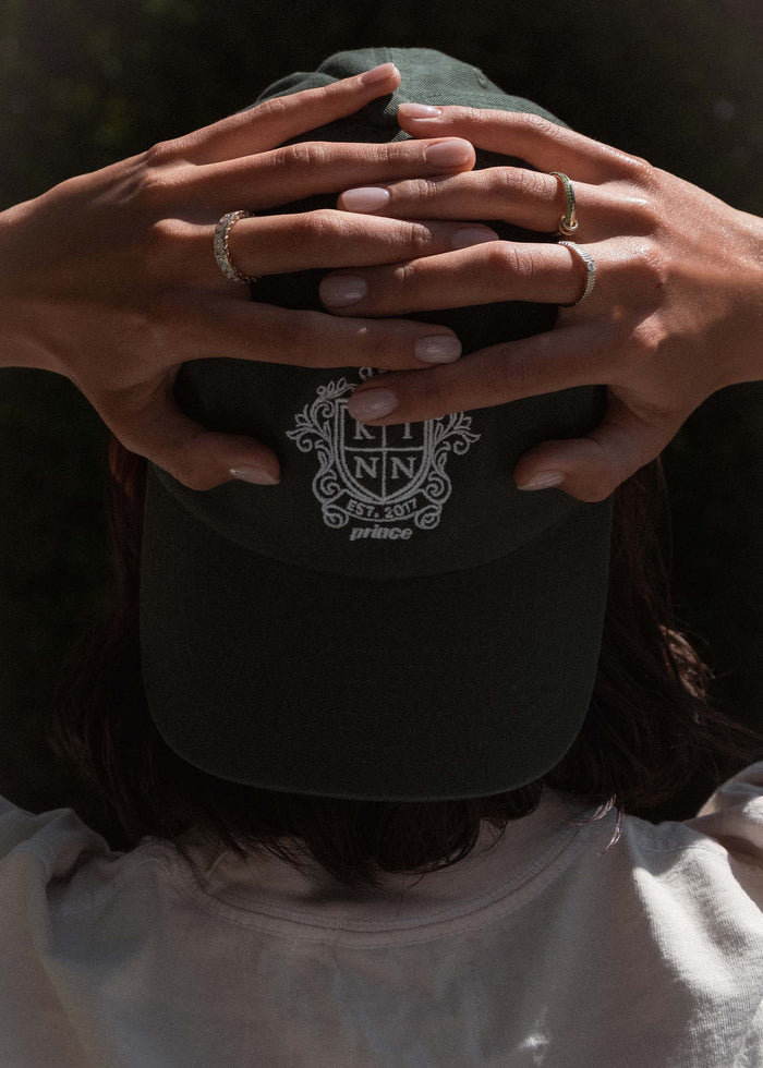 woman wearing a backwards Kinn x Prince The Club Cap holding her hands behind her head