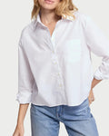 Woman wearing a white shirt and blue jeans against a plain background