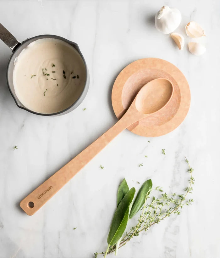 Top view of Tool Rest- Natural Round showcasing carved spoon notch and smooth natural wood finish with wooden spoon and saucepan on marble counter