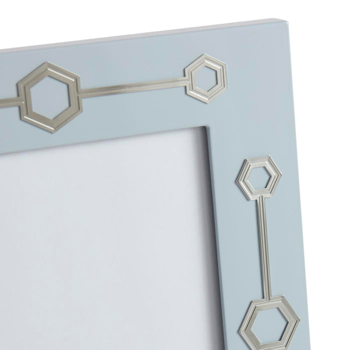 Close-up of a decorative mirror with geometric frame details on a light blue background