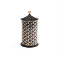A cylindrical lidded storage jar with a black and beige geometric pattern, featuring a black lid with a small beige knob, set against a plain white background.