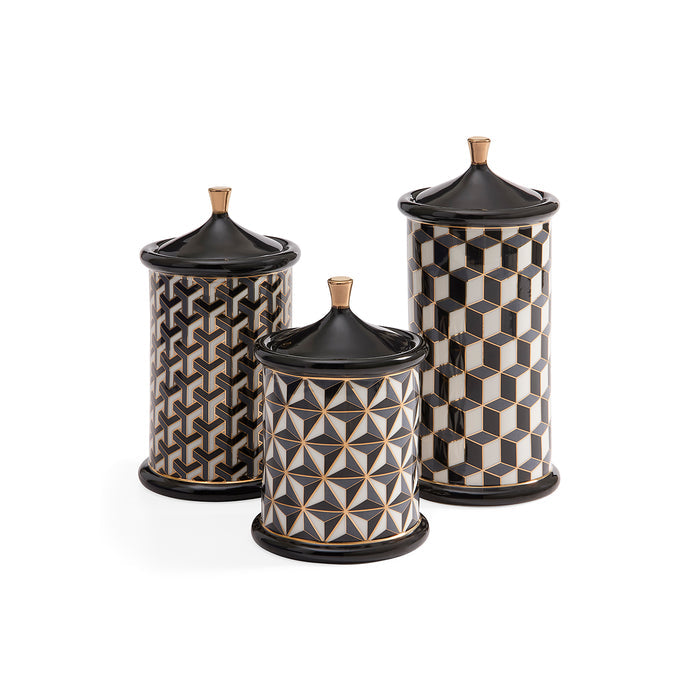 Three cylindrical lidded canisters with black lids and bases, featuring geometric black, white, and gold patterns, arranged on a white background.