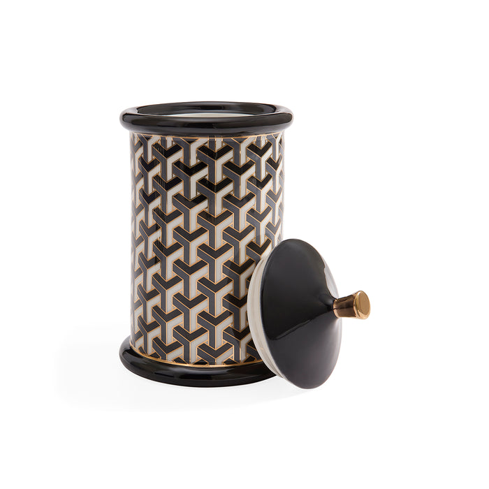 A cylindrical ceramic jar with a black and beige geometric interlocking pattern, featuring a matching black lid with a brass knob, set against a plain white background.