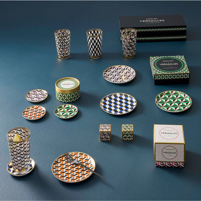 Collection of patterned ceramic items including plates, tumblers, and boxes on a blue background with 'Versailles' branding.