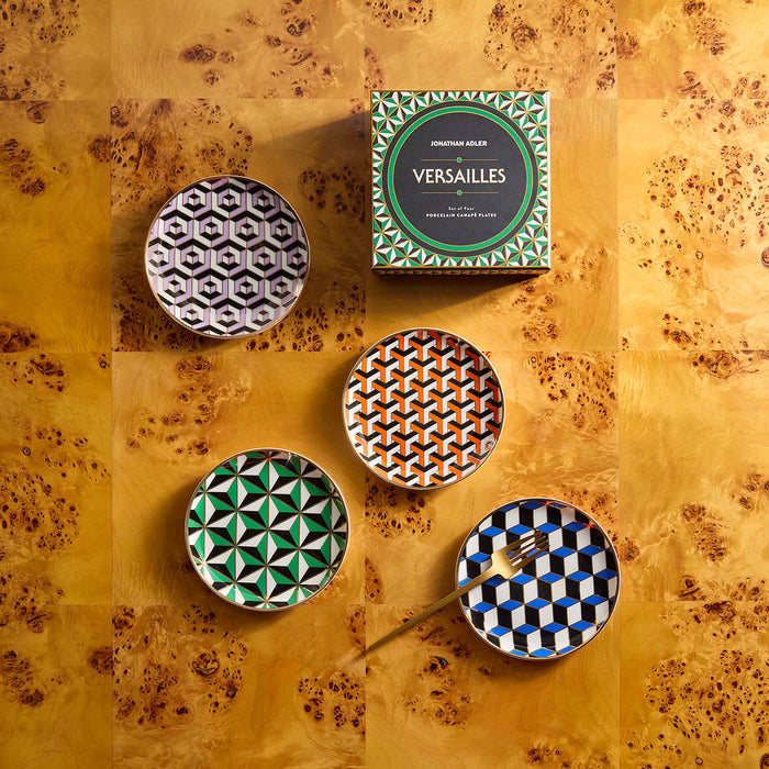 Four patterned plates with a box labeled 'Versailles' on a textured surface.