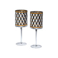 Two clear stemmed glasses with cylindrical bodies featuring a black, white, and gold geometric cube pattern, shown on a plain white background.