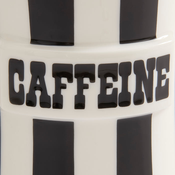 Close-up of a white cylindrical product with bold black vertical stripes and the word 'CAFFEINE' in large black letters across the center.
