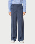 Person wearing a light blue shirt and dark gray pleated pants on a plain background