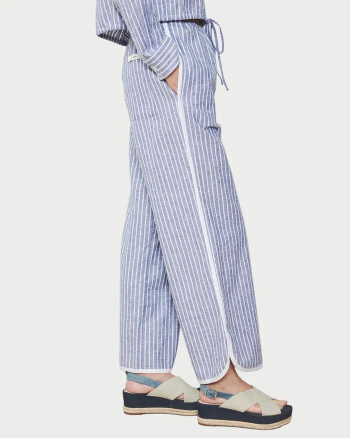 Person wearing a blue and white striped outfit with wide-leg pants on a wooden floor.