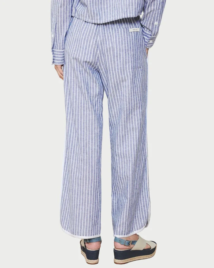 Person wearing a blue and white striped outfit with wide-leg pants on a plain background