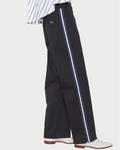 Black pants with white stripes worn by a person on a wooden floor.